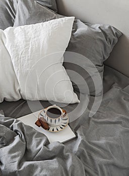 A lazy, unhurried weekend morning. Black coffee, magazine in bed with linen bedding, top view photo