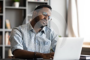 Lazy unmotivated African American businessman looking at laptop screen