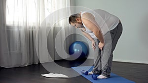 Lazy unmotivated man throwing dumbbells on floor, hopelessness, insecurities