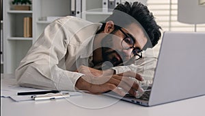 Lazy weary sleepy male manager tired exhausted Arabian Indian businessman employee working computer boring remote job