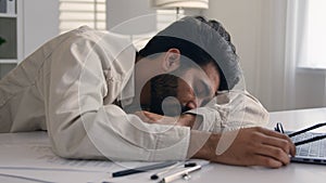 Lazy weary sleepy male manager tired exhausted Arabian Indian businessman employee working computer boring remote job