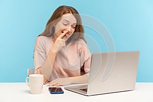 Lazy woman employee picking nose and looking into laptop screen with careless expression, talking on video call