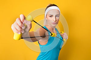 Lazy woman performs exercises for muscles hands with resistance band, isolated on yellow background. Half length of fit