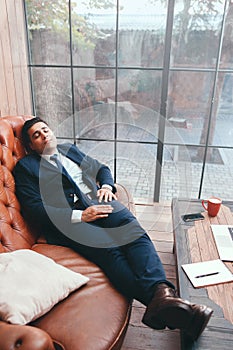 Lazy worker lying on sofa in office photo
