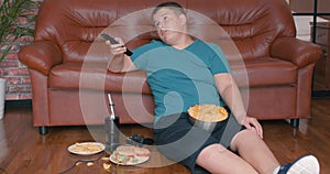 lazy young boy sitting on floor holding remote control