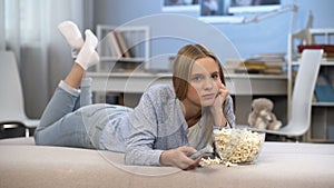 Lazy young woman wasting time in front of home television, changing channels