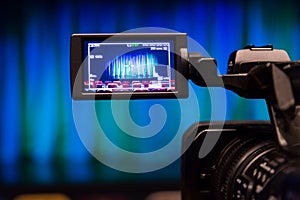 The LCD display on the camcorder. Videography in the theater. Blue-green curtain on the stage