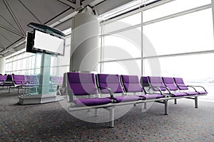 LCD TV and row of purple chair at airport