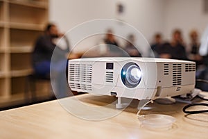 LCD video projector at business conference or lecture in a conference room or office with blurred people background