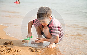 le boy playing sand on the beach summer time