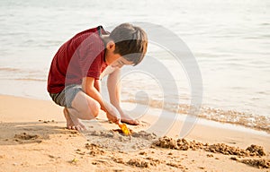 le boy playing sand on the beach summer time