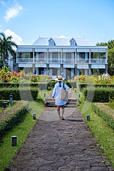 Le Chateau de Bel Ombre Mauritius, old castle in tropical garden in Mauritius, woman walking in a garden of an old