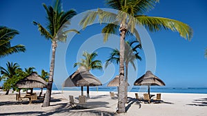 Le Morne beach Mauritius,Tropical beach with palm trees and white sand blue ocean and beach beds with umbrella,Sun