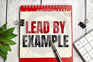 lead by example words on notepad and pen on wooden background