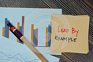 Lead by Example write on sticky notes isolated on Wooden Table