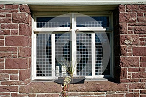 Lead Paned Window Set in Red Brick Wall With Decorative Flower Pot