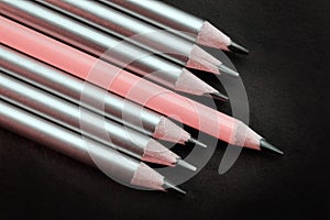 lead pink pencil different from others silver pencils on a black background