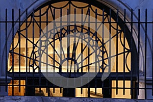 Leaded glass transom window behind an iron fence