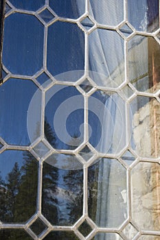 Leaded glass window reflects blue sky and trees