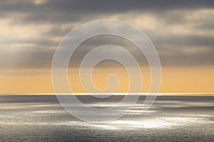 Leaden clouds and rays of the sun through them over the ocean