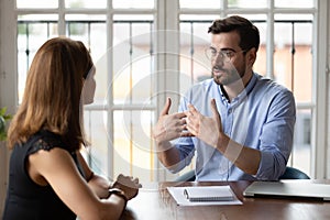 Leader in eyeglasses explaining project details to new female employee.