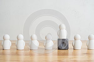 Leader standing out from the crowd on wood table with white wall background and copy space. Leadership and management