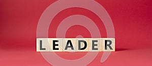 Leader symbol. Concept word Leader on wooden cubes. Beautiful red background. Business and Leader concept. Copy space