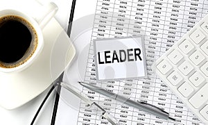 LEADER text on sticky on chart with coffee,pen and calculator