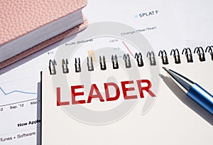 LEADER text written on notepad with pen on financial documents