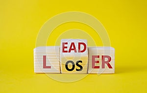 Leader vs Loser symbol. Wooden cubes with words Loser and Leader. Beautiful yellow background. Leader vs Loser and business