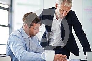 Leadership is an action not a position. two businesspeople having a discussion in a corporate office.