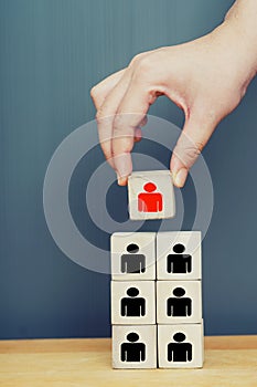 Leadership concept. Hand holding a top of wooden blocks pyramid with people icons