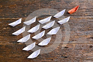 Leadership concept with orange paper ship leading white ship on photo