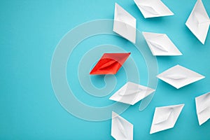 Leadership concept. Red leader paper ship leading among white on blue background