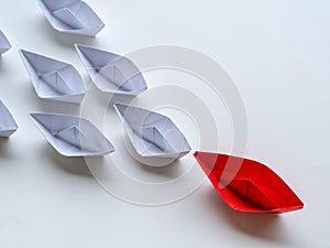 Leadership concept. Red paper ship lead among white. One leader
