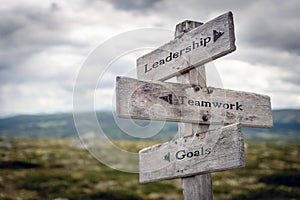 Leadership, teamwork and goals text on wooden sign post outdoors in landscape scenery