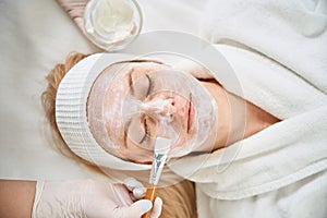 Leading expert in cosmetology applying alginate mask on female client face