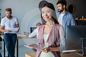 Leading her team to success. Confident young woman holding digital tablet and looking at camera with smile while her