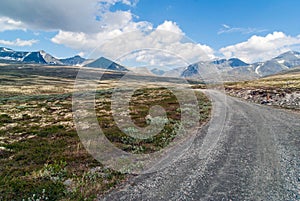 Leading lines and gravel road towards mountains photo