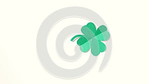 A leaf of clover cut out of paper is spinning on a white background.