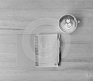 Leaf latte art coffee and notebook with pen