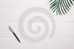 Leaf and pen on wooden table, composition with top view, branch and leaves on wood desk with copy space.