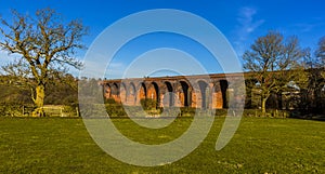 Leafless winter trees frame the Victorian railway viaduct for the London and North Western Railway at John O`Gaunt valley