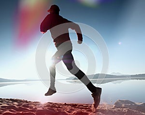 Leakage of light in the lens. . Running man. Sportsman run, jogging guy during the sunrise above sandy beach.