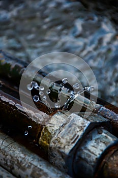 Leaking water from a joint pipe on the street. Water splashing and dripping from the valve joint