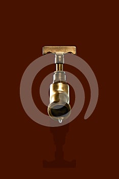 Leaky antique brass tap, isolated on brown background