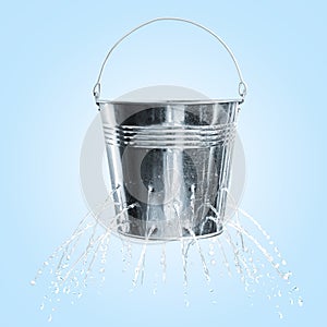 Leaky bucket with water on blue background