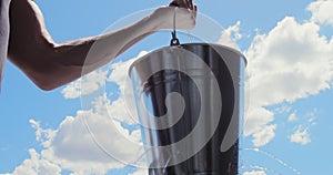 Leaky bucket with water dripping against blue sky, Metaphor. Leaking profits etc