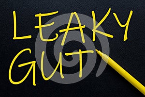 Leaky Gut Yellow Pen with yellow text own rent at the black background