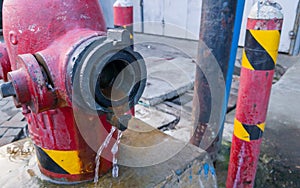 A leaky red hydrant pump near street